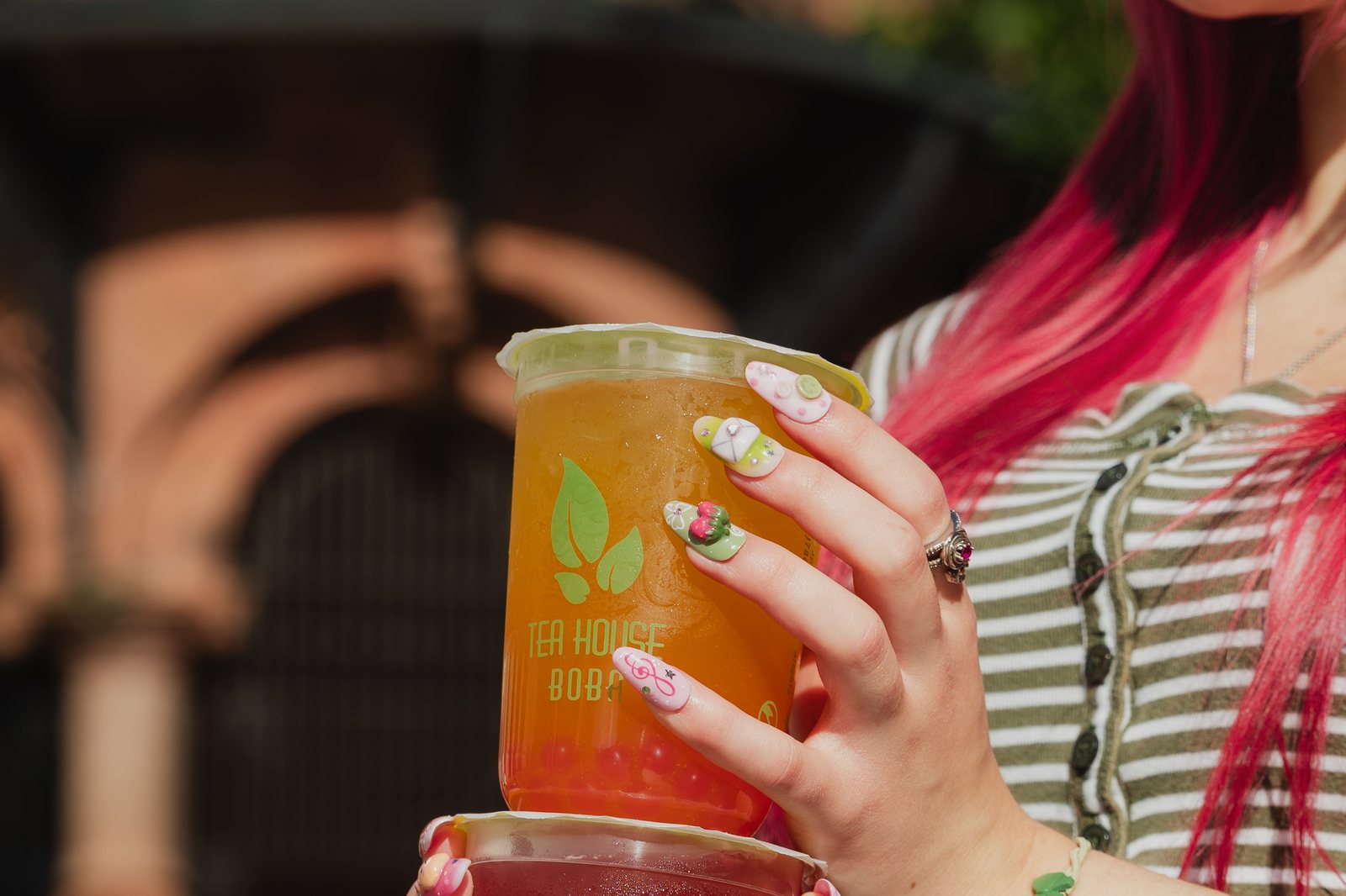 Model holding two Tea House Boba drinks